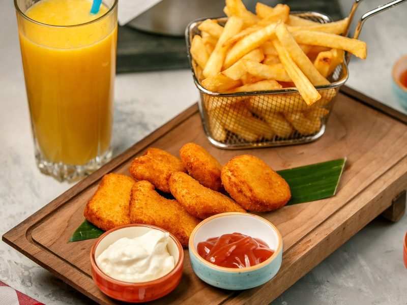 fried nuggets and french fries on wooden board